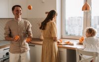Family bonding in a bright kitchen, juggling oranges and sharing laughter.